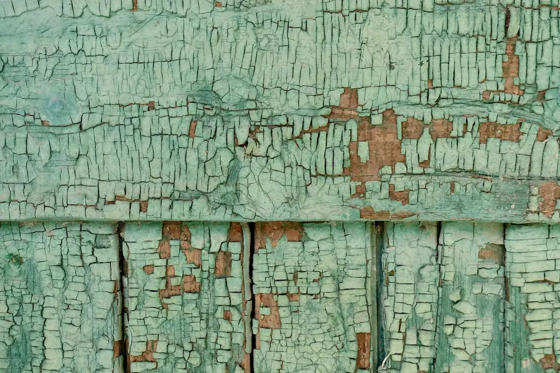 Peinture écaillée sur du bois ancien, laissant apparaître les couches inférieures